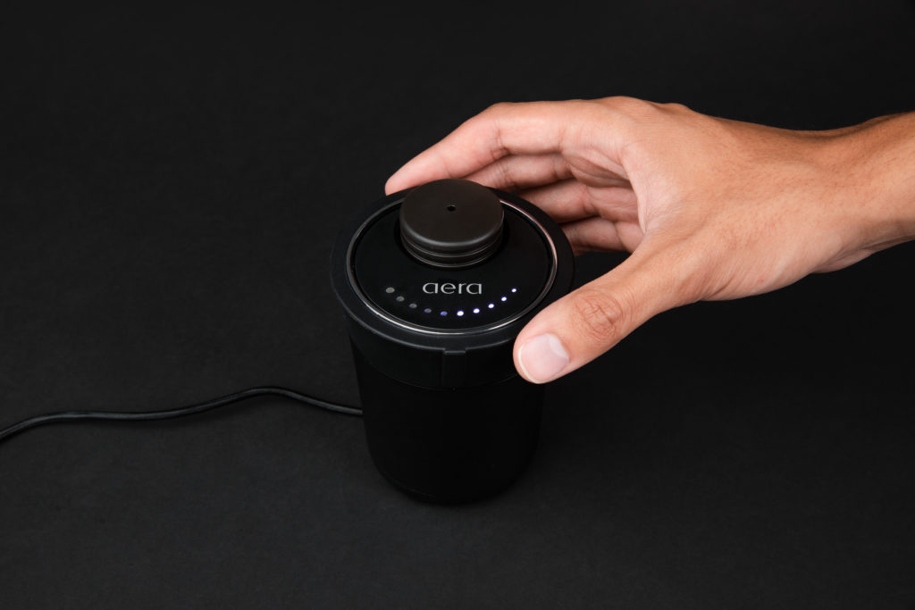Darstellung der Bedienung des AERA Go Car Diffusers. Eine Hand bedient den Drehregler.